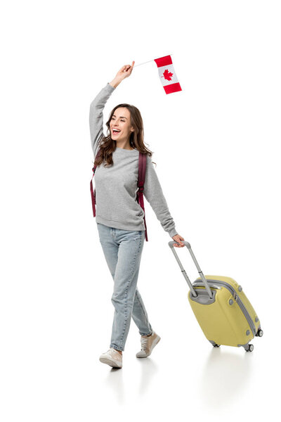cheerful female student with suitcase and canadian flag isolated on white, studying abroad concept
