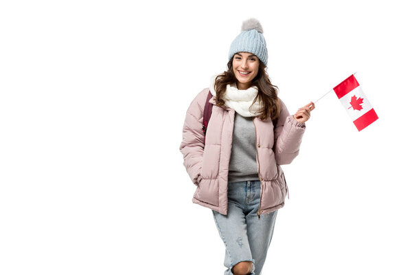 улыбающаяся студентка в зимней одежде с канадским флагом и смотрящая на камеру, изолированную на белом
