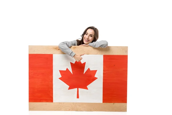 女性カナダ国旗と木の板の後ろに座って 白で隔離のサインを親指を表示 — ストック写真