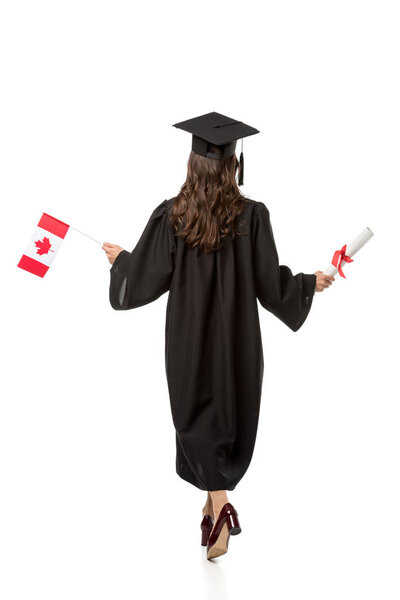 back view of female student in academic gown holding canadian flag and diploma isolated on white