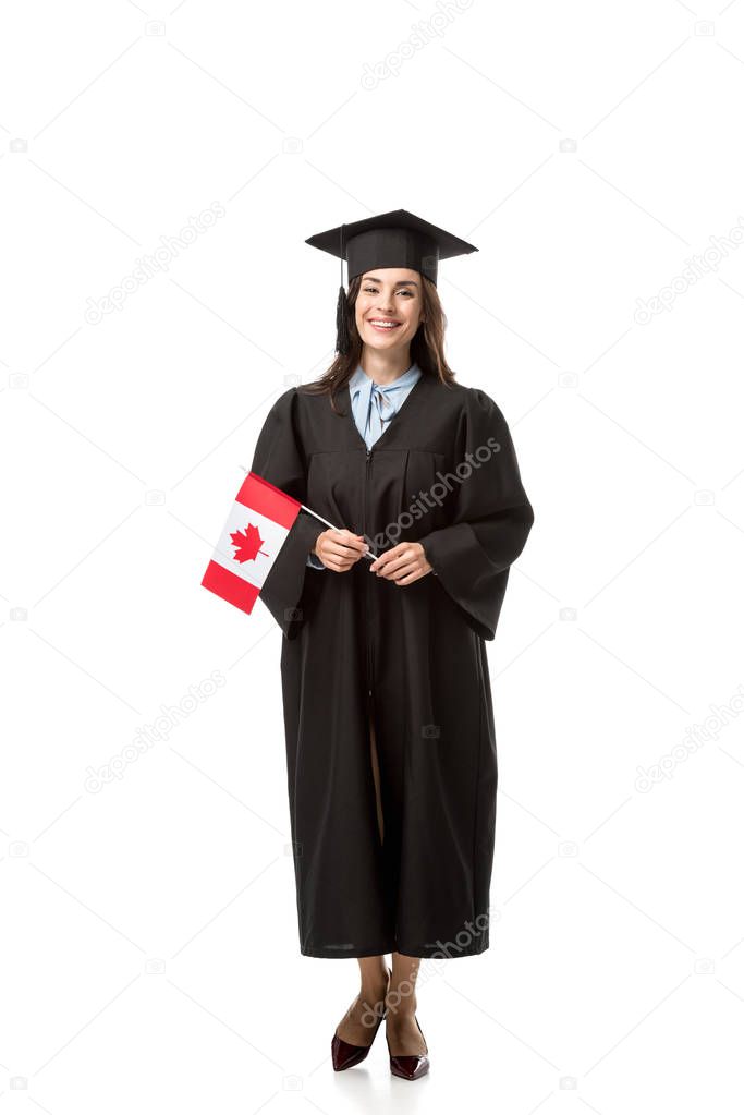 beautiful smiling female student in academic gown holding canadian flag isolated on white