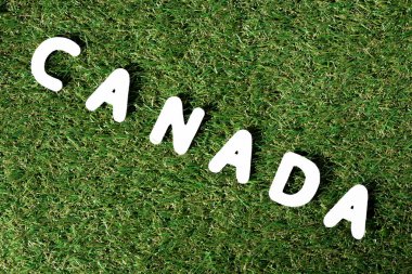 yeşil çimenlerin üzerinde arka plan beyaz harflerle kelime 'Kanada' yapılmış