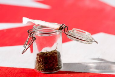 cannabis in glass jar with joint on canadian flag, marijuana legalization concept clipart