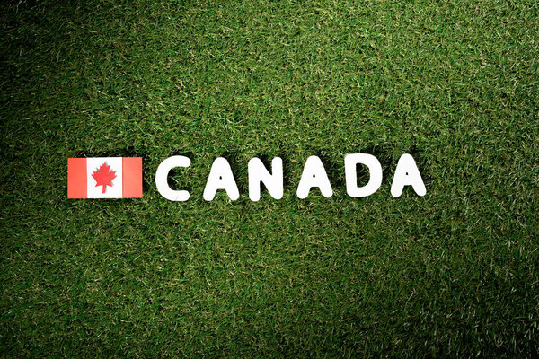 вид сверху слова "Канада" с канадским флагом на зеленом фоне травы
