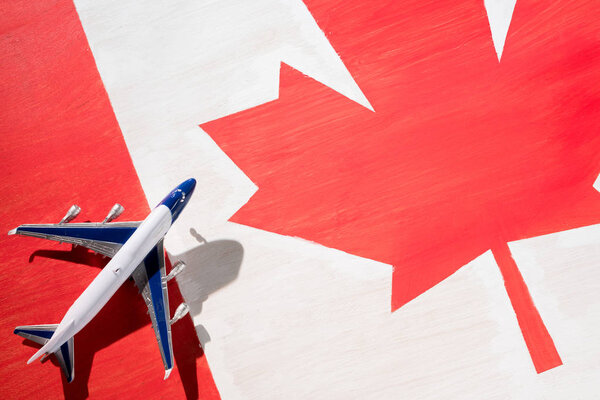 модель самолета с канадским флагом на фоне, иммиграционная концепция
