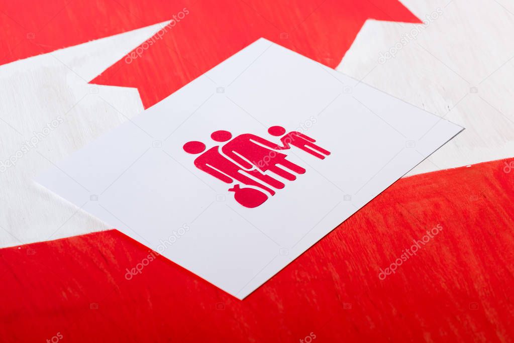 selective focus of white card with family icon on canadian flag, immigration concept