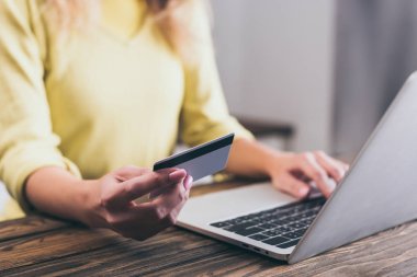 kredi kartı laptop yakınındaki evde tutan kadın kırpılmış görünümünü