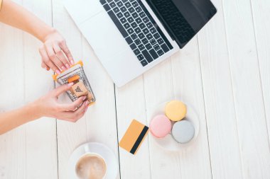 üstten görünüm kadın tutmak oyuncak laptop, kupa ve macaroons yakınındaki küçük kağıt kutuları ile arabası alışveriş