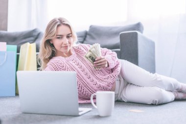 neşeli kadın doları banknot evde tutarken laptop arıyorum