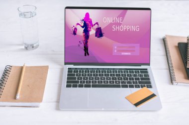 Notebook ve laptop ekran üzerinde Web sitesi ve ahşap masa üzerinde kredi kartı alışveriş 
