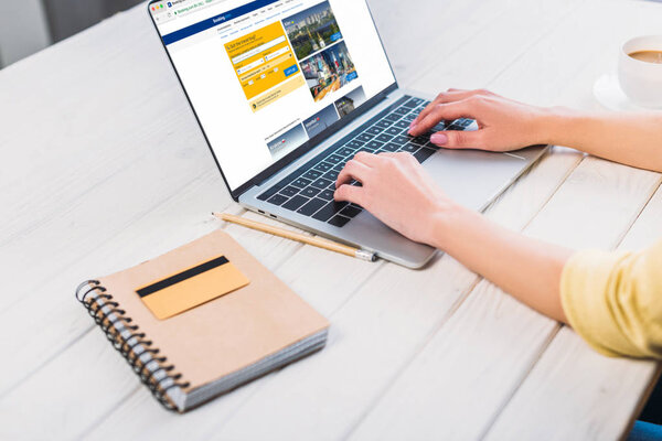 обрезанный вид женщины с помощью ноутбука с бронированием веб-сайт на экране
 