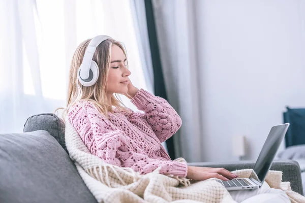Ξανθιά Γυναίκα Ακούγοντας Μουσική Στα Ακουστικά Ενώ Κάθεται Στο Σπίτι — Φωτογραφία Αρχείου
