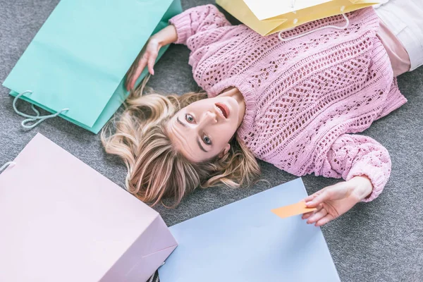 Vista Superior Mujer Sorprendida Sosteniendo Tarjeta Crédito Acostado Suelo Cerca — Foto de Stock