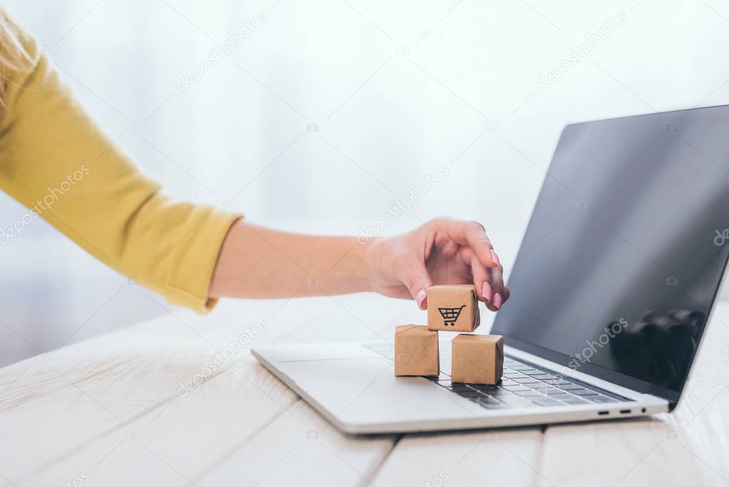 cropped view of woman putting small paper box on laptop