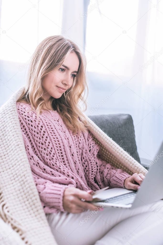 attractive blonde woman shopping online and holding credit card 