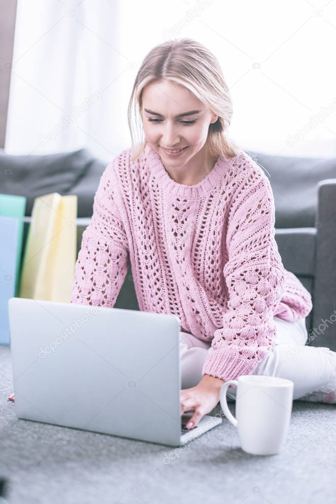 cheerful  blonde freelancer typing on laptop while working at home