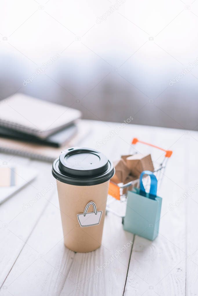 selective focus of paper cup with symbol near toy cart with boxes 