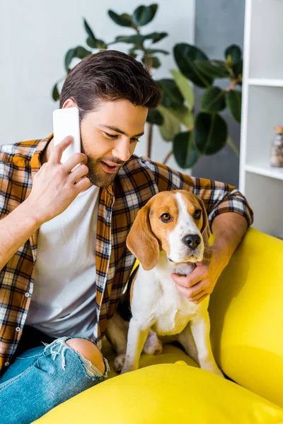 スマート フォンで話していると 犬を見て市松模様のシャツでハンサムな男 — ストック写真