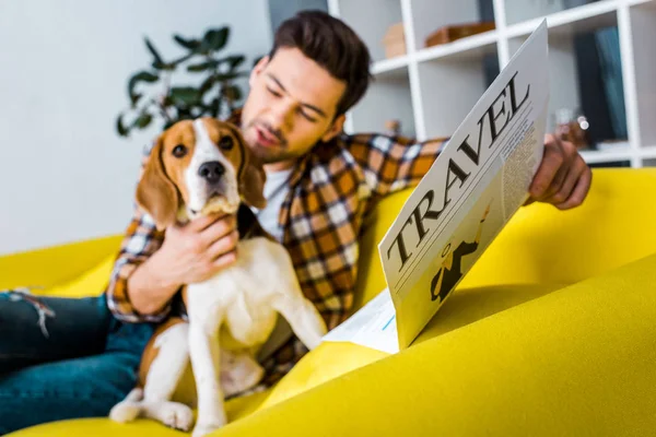 快乐的人坐在沙发上与猎狗坐在沙发上的选择性焦点阅读旅游报纸 — 图库照片