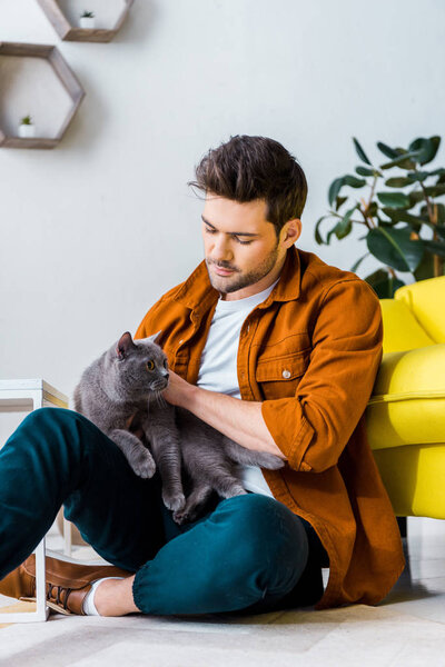 casual smiling man sitting on floor with cute cat