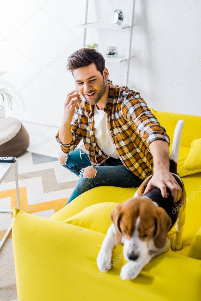 happy young man talking on smartphone and looking at dog