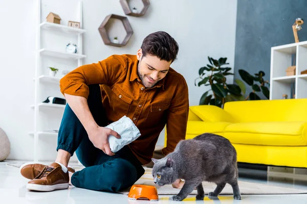 幸せな若い男グレー摂食ブリティッシュショートヘア猫自宅 — ストック写真
