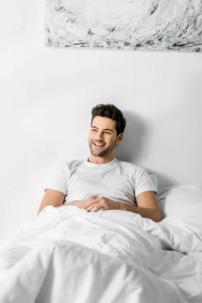 朝はベッドで横になっている若いハンサムな陽気な男 — ストック写真