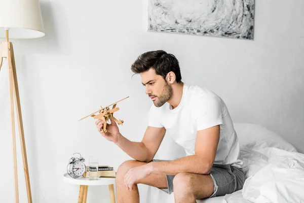 Handsome Young Man Looking Wooden Toy Plane Bedroom — Stock Photo, Image