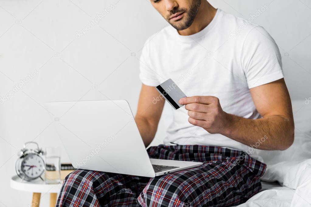 cropped view of man shopping online with credit card and laptop