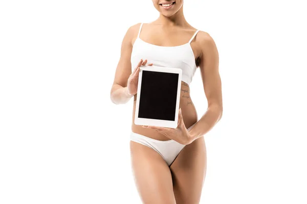 裁剪拍摄微笑的非洲裔美国女孩在白色内衣举行数字平板电脑与空白屏幕孤立在白色 — 图库照片