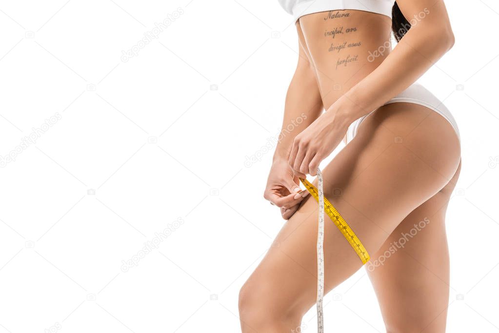 cropped shot of african american girl in underwear measuring leg with tape isolated on white
