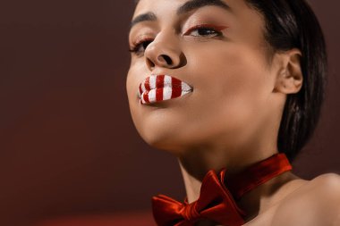 burgundy üzerinde izole kamera bakarak yaratıcı makyaj ile Afrika kökenli Amerikalı kızın düşük açılı görünüş