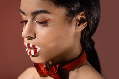 kırmızı papyon ve sanatsal makyaj üzerinde izole burgundy seyir ile güzel Afro-Amerikan Kız