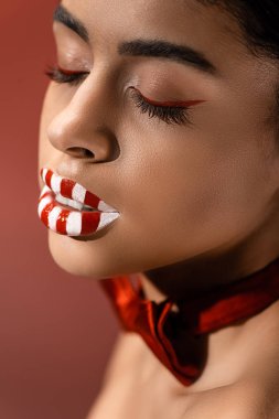 yakın çekim yaratıcı makyaj ve burgundy üzerinde izole kapalı gözler güzel baştan çıkarıcı Afro-Amerikan kız görünümünü