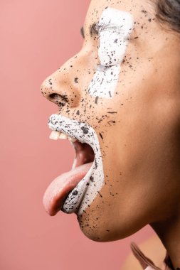 Afro-Amerikan Kız boya ile yan görünüm üzerinde izole pembe dilini gösterilen yüzündeki su sıçramalarına 