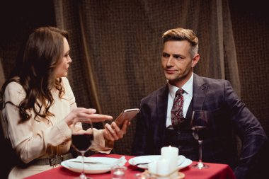 akıllı telefon tutarak ve restoranda romantik tarih sırasında memnun adamla tartıştığını kadın