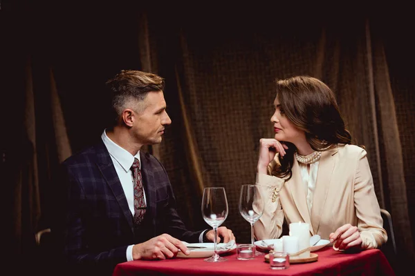 beautiful couple sitting at table and looking at each other during romantic dinner in restaurant