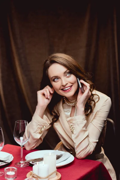 Όμορφη Χαμογελαστή Γυναίκα Κάθεται Στο Τραπέζι Και Μιλάμε Για Smartphone — Φωτογραφία Αρχείου