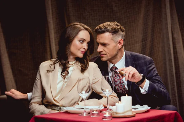 beautiful couple sitting at table and looking at each other during romantic dinner in restaurant