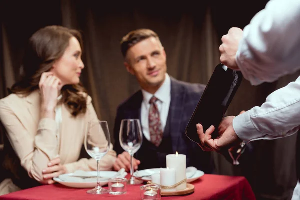 レストランでロマンチックな日付の間に美しいカップルにワインのウェイターを示すボトルの選択と集中 — ストック写真