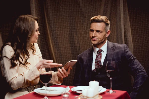 Woman Holding Smartphone Arguing Dissatisfied Man Romantic Date Restaurant — Stock Photo, Image