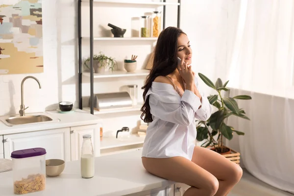 Hermosa Mujer Camisa Blanca Sentada Mostrador Cocina Hablando Teléfono Inteligente —  Fotos de Stock