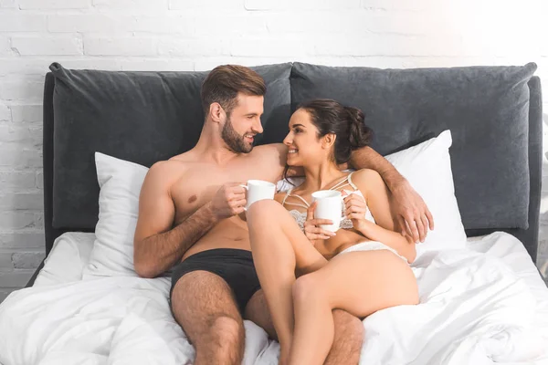 Vackra Sexiga Par Liggande Med Kaffekoppar Sängen Leende Och Tittar — Stockfoto