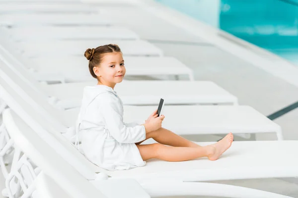 Niedliche Kind Weißen Bademantel Hält Smartphone Der Nähe Von Schwimmbad — Stockfoto