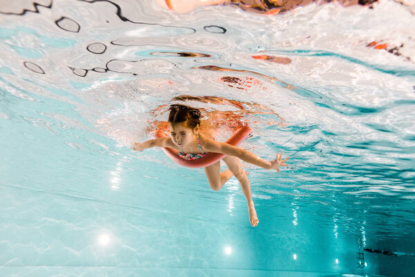 cute child with closed eyes swimming underwater in swimming pool 