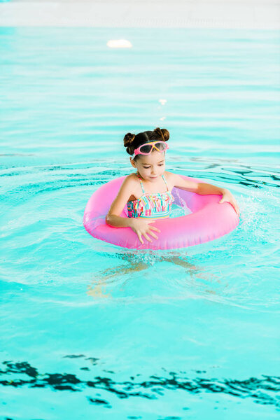 happy kid swimming with inflatable ring in swimming pool