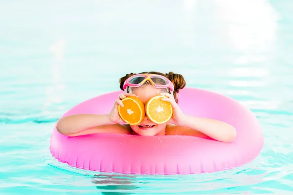 Happy Child Holding Half Oranges Eyes While Swimming Inflatable Ring — Stock Photo, Image