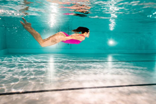 妇女在蓝色的水中潜水在游泳池 — 图库照片