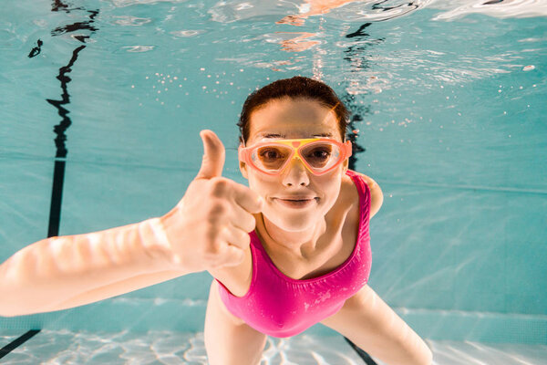 cheerful woman showing thumb up while diving underwater 
