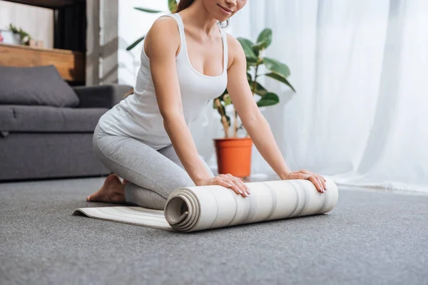 裁剪视图的妇女滚动健身垫练习瑜伽在家里 — 图库照片